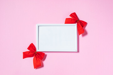 Empty picture frame and wooden date calendar with two red ribbons on purple background. Creative and cool celebration of love concept