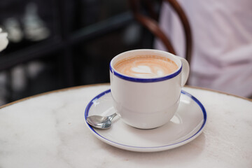 One Cup of cappuccino with latte art. Coffee in blue cup on wooden table in cafe. Concept of easy breakfast.