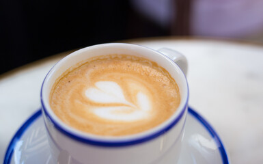 One Cup of cappuccino with latte art. Coffee in blue cup on wooden table in cafe. Concept of easy breakfast.