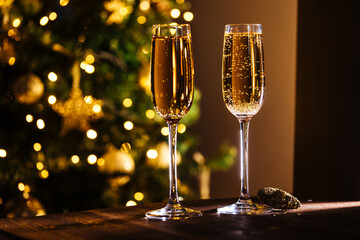 Two glasses of champagne with Christmas festive lights in blurry background. Celebration mood and close up