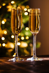 Two glasses of champagne with Christmas festive lights in blurry background. Celebration mood and close up