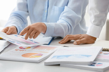 Businessman and his female colleague working with documents at desk, closeup