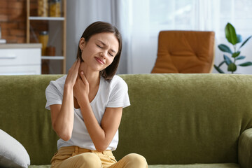 Young woman feeling neck pain at home