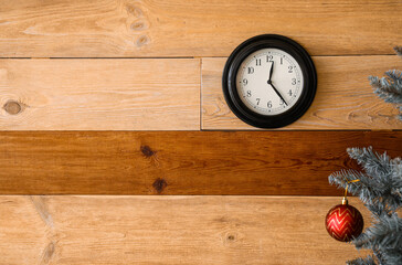 Christmas tree and black clock on wooden wall