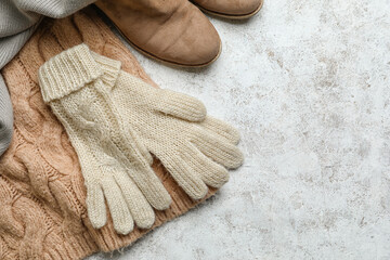 Knitted gloves, shoes and clothes on light background, closeup