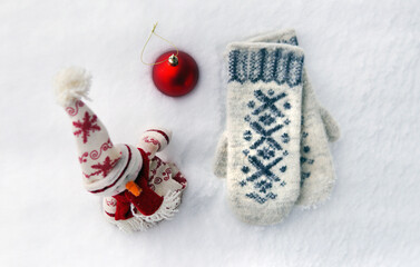 Snowman red ball and mittens in the snow. Top view
