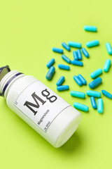 Bottle of magnesium pills on green background, closeup