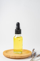 Natural lavender homemade essential oil. Spa products for home beauty procedures. bottle with dropper and dry lavender flowers on wooden plate on white backgriound
