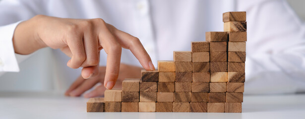 The fingers of a business woman walking on wooden blocks stacked in steps. Business Investment and Financial Accounting Ideas for a Successful Growth Process