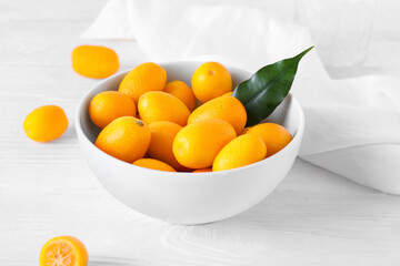 Bowl with tasty kumquat fruits  on light background