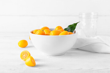 Bowl with tasty kumquat fruits  on light background