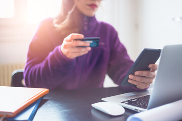 Woman paying a bill through a smartphone using NFC technology in a restaurant. Satisfied customer paying via mobile phone using contactless technology. Close up mobile payment hands in a coffee shop