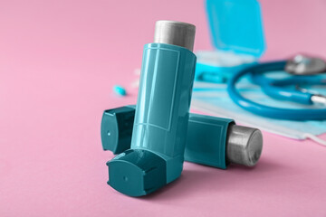 Asthma inhalers on pink background, closeup
