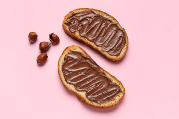 Bread with chocolate paste and hazelnuts on pink background
