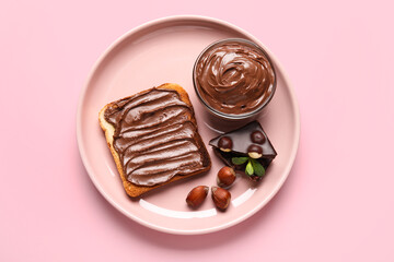 Plate of bread with chocolate paste and hazelnuts on pink background