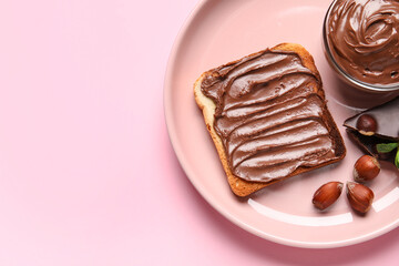 Plate of bread with chocolate paste and hazelnuts on pink background, closeup