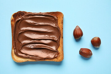 Bread with chocolate paste and hazelnuts on blue background