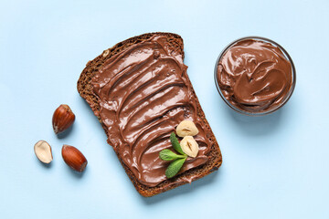Bread with chocolate paste and hazelnuts on blue background