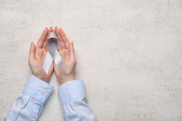Female hands with Parkinson's awareness ribbon on grunge background
