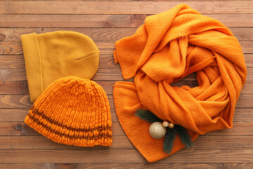 Hats, scarf and Christmas decor on wooden background