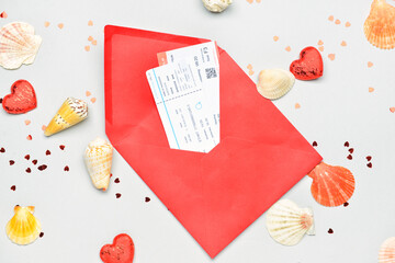 Fototapeta na wymiar Envelope with tickets, hearts, confetti and seashells on light background. Valentine's Day celebration