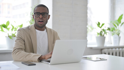 African Man Feeling Shocked while using Laptop in Office