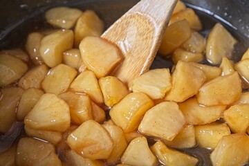 Cooked apple pieces in casserole pot with bamboo spoon