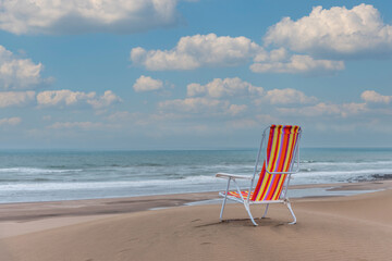 Empty striped beach chair on top of a dune facing the sea. Horizontal photo