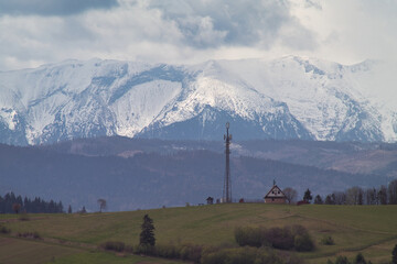 Ośnieżone góry Tatry wiosną, w tle maszt i domek.