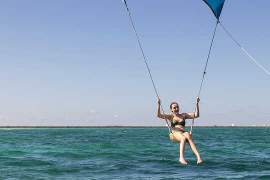 Girl having fun with a spinnaker ride behind a boat. She is floating in the air above the Caribbean sea