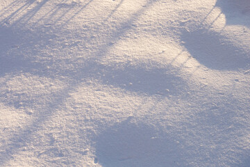 Background with a fragment of an uneven snow surface with pits and shadows