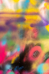 Colorful  and splattered spray paintgraffiti over a cracked surface or concrete wall wiyh many colors