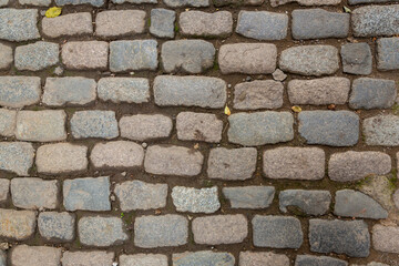 Paving stones from granite. The stones are gray and red. Old stone roads.