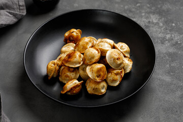 Fried dumplings on a black plate. Russian dish. Dumplings. Close up