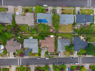 Aerial view. Small green suburb. Roofs of one-story buildings, paved roads, cars. Lots of trees, bushes, green lawns. Real estate objects, construction planning.