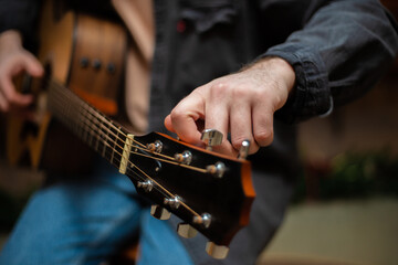 A guy clamps a chord on an acoustic guitar with close-up