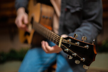 A guy clamps a chord on an acoustic guitar with close-up
