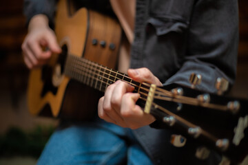 Fototapeta na wymiar A guy clamps a chord on an acoustic guitar with close-up