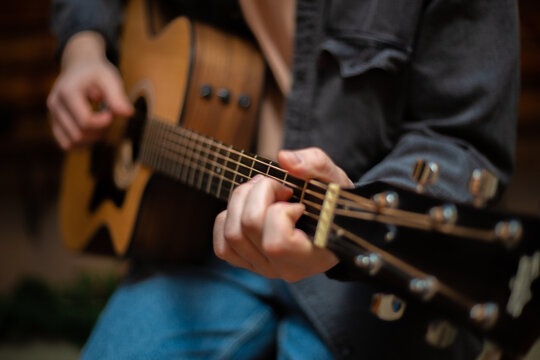 A guy clamps a chord on an acoustic guitar with close-up - Powered by Adobe