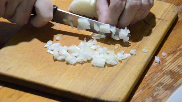 Slicing onions with a knife on a kitchen board