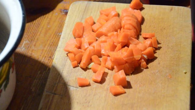 Slicing boiled carrots with a knife on a kitchen b