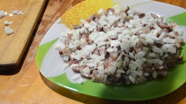 Sprinkle onions on chopped herring for salad 
