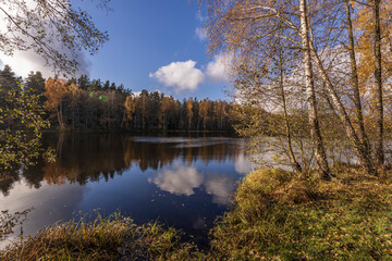 Sunny autumn in the park. Autumn landscape with colorful yellow, orange and red trees and reflection in the pond.
