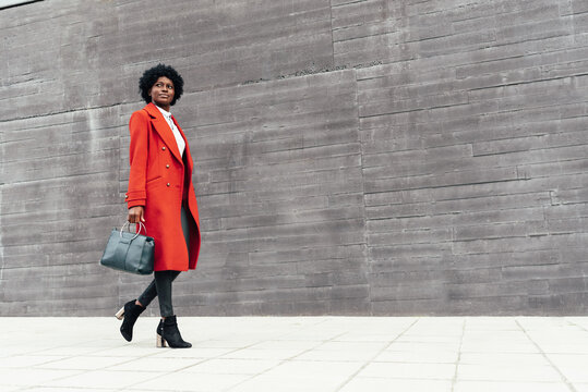 Stylish Afro American woman looking away while walking down the street. Urban lifestyle concept.