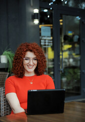 Curly hair business woman in red clothes works with laptop ooutdoors.
