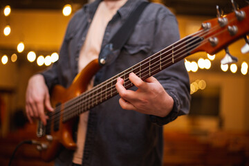 Obraz premium A young guy with a beard plays a bass guitar with five strings