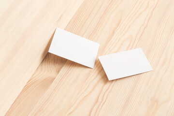 Two white business cards against bright wood  background. Front view.	
