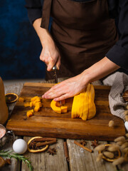 The chef slices a fresh orange pumpkin to make a traditional American pumpkin pie. on a wooden cutting board. Close-up. Restaurant, hotel, pastry shop, home cooking.