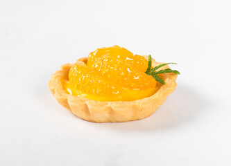 Tartlet with custard and slices of tangerines covered with syrup on a light background. Close-up