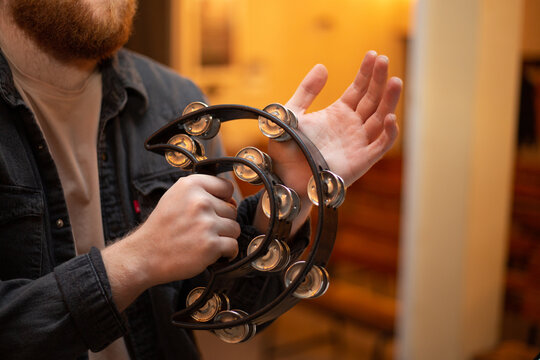 A young guy with a beard plays the tambourine